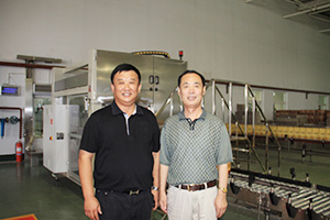 時任山東省農業(yè)廳廳長戰(zhàn)樹毅與威龍總經理孫硯田在威龍全自動灌裝生產線前合影